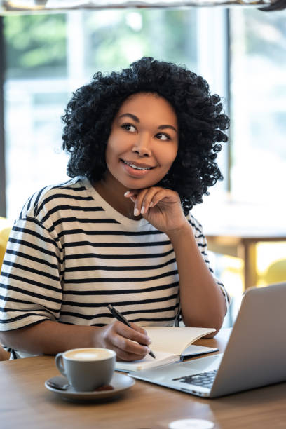 istock Woman sitting at the table and making notes to a notebook 2165416306