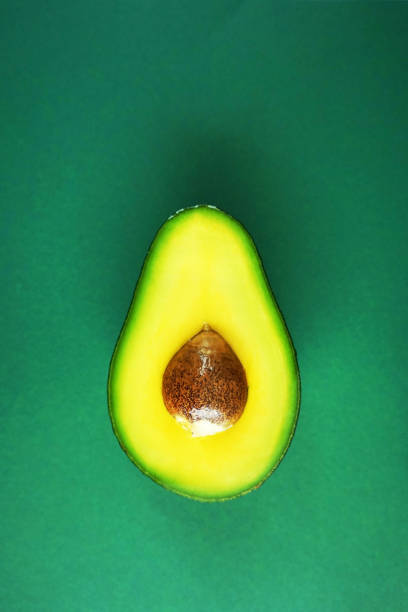 istock Half of cut avocado on green background 2165419511