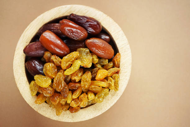 istock Dried dates and raisins in a wooden plate 2165419691