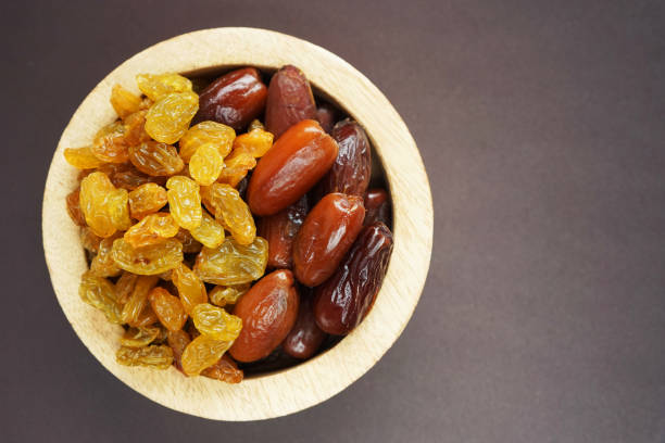 istock Dried dates and raisins in a wooden plate 2165419744