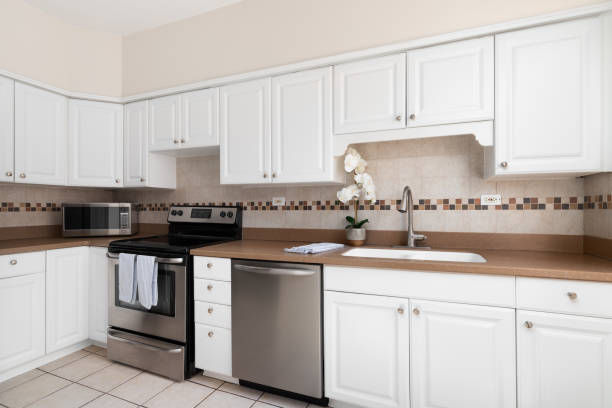 istock A kitchen with white cabinets, brown countertop, and tiled backsplash. 2165422735