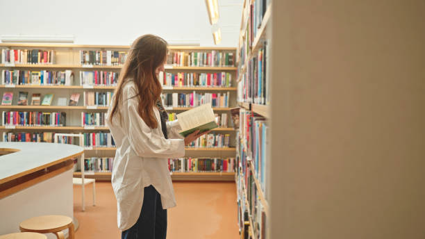 istock Unrecognizable brunette browsing a book in a library or bookstore 2165423559