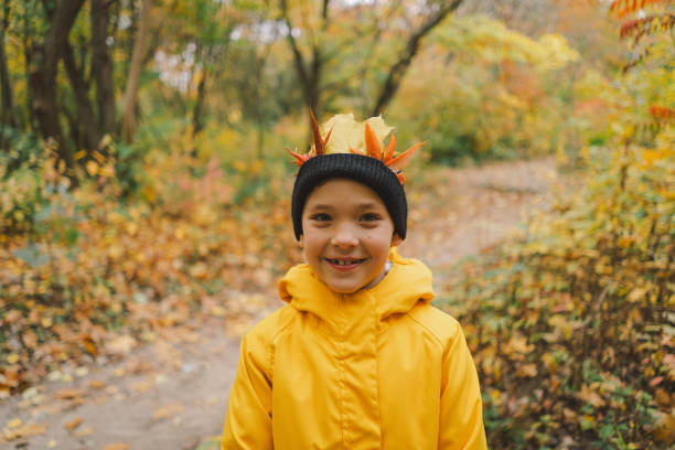 istock Child dressed in a bright yellow raincoat walks along a serene forest 2165432895