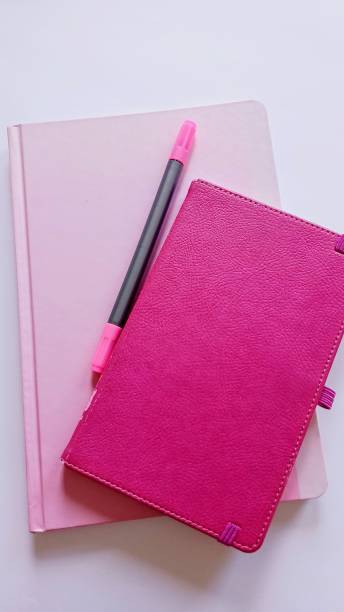 istock pink notebooks and pen on white background 2165435151