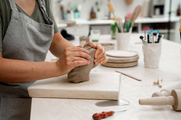 istock Wedging the clay before starting making a pottery project to create proper consistency. Removing air bubbles from clay before modeling to avoid the ruination of a ceramic product. 2165436635