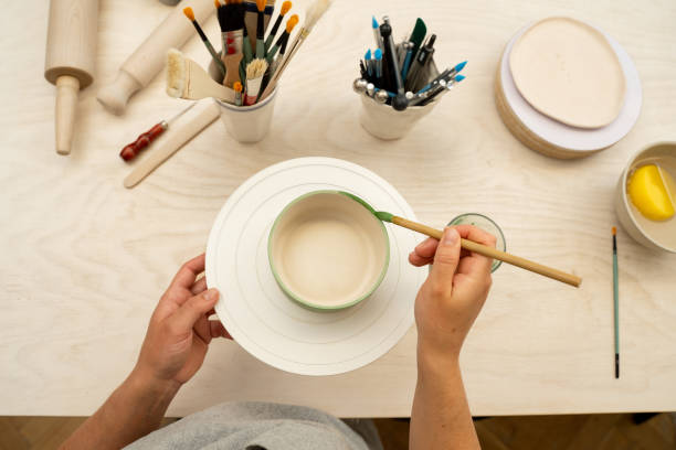 istock Learning how to paint a handmade pottery project. Decorating a clay product with bright green color. Using a brush to paint a ceramics bowl. 2165436653