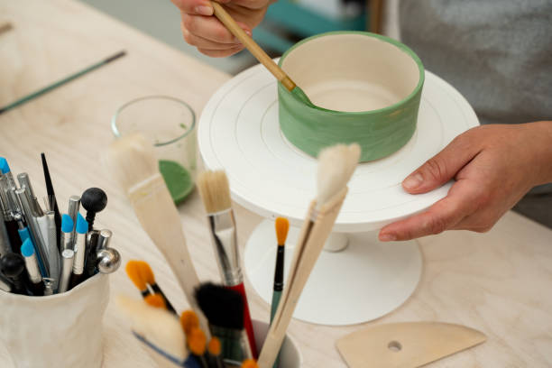 istock Using a brush to paint a ceramics bowl. Learning how to paint a handmade pottery project. Girl is decorating a clay product with bright green color. 2165436662