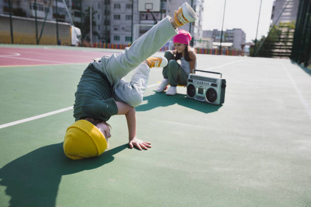 Little b-boy practices breakdancing / breaking on a street playground. Baby freeze. Street dance. Hip hop culture.