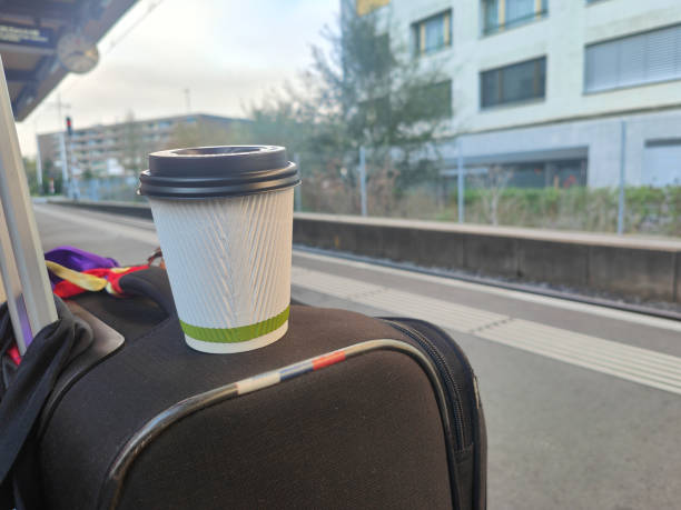 Paper coffee cup above a large luggage at train station