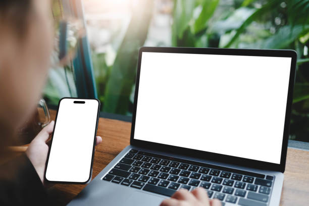 istock A blank screen for hand typing text,using laptop and mobile phone contact business searching information in workplace on desk at office. 2165452111