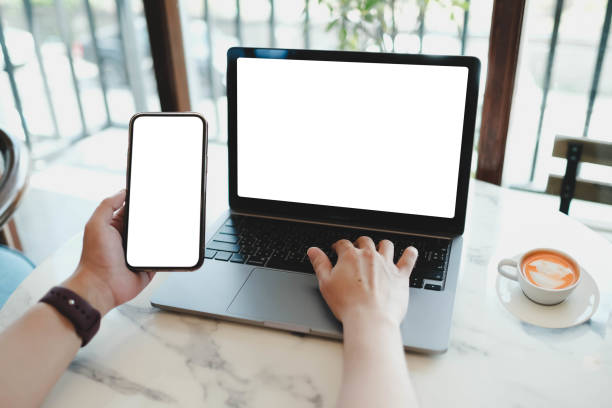 istock A white blank screen for hand typing text,using laptop and mobile phone contact business searching information in workplace on desk at office. 2165452176