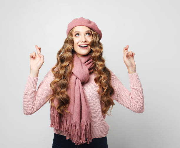 istock optimistic blond woman cross fingers for dream come true over grey background 2165463519