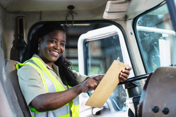istock Black woman truck driver with clipboard smiling at camera 2165464355
