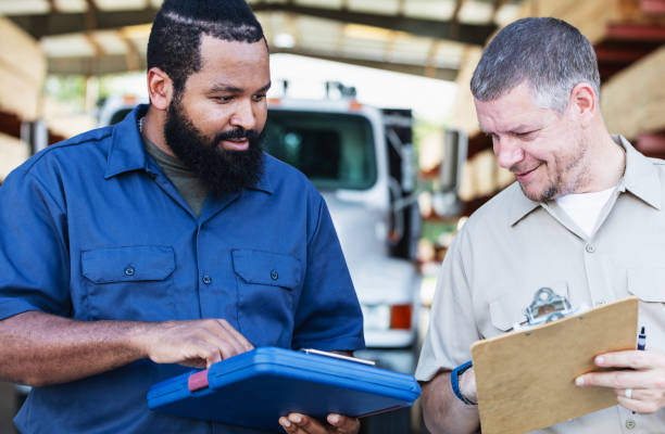 istock Two multiracial men working in lumberyard, with clipboards 2165464475