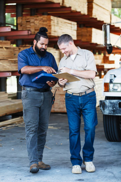 istock Two multiracial men working in lumberyard, with clipboards 2165464476
