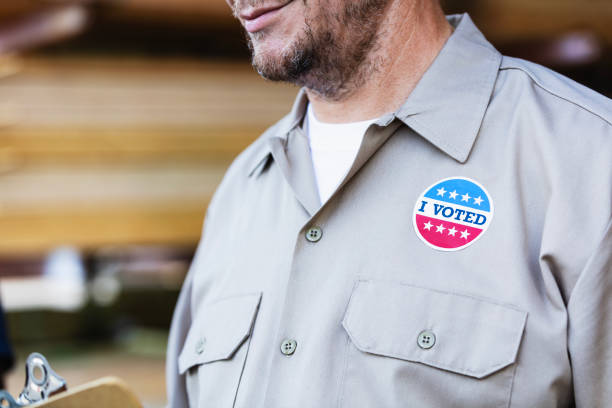istock Man in lumberyard, with I Voted sticker 2165464479