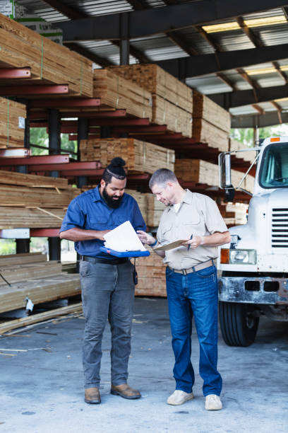 istock Two multiracial men working in lumberyard, with clipboards 2165464480