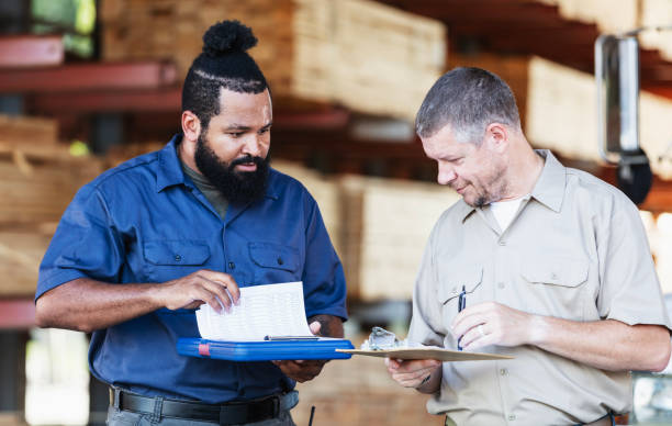 istock Two multiracial men working in lumberyard, with clipboards 2165464481