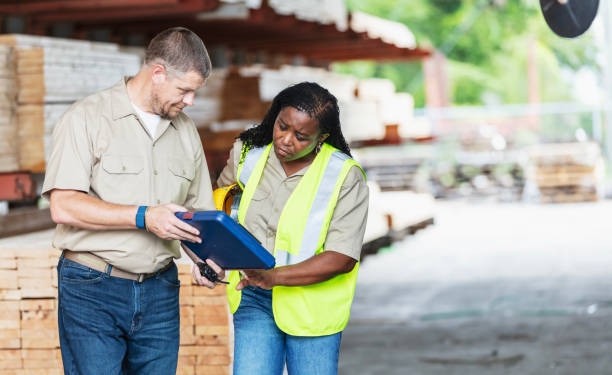 istock Two workers looking at clipboard in lumberyard 2165464518