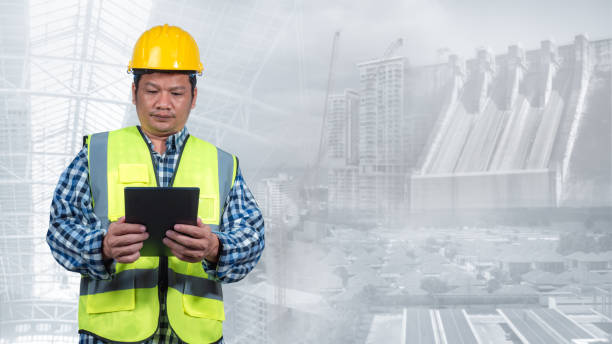 istock Engineer working with tablet with double exposure background of clean energy power generation source. Engineer inspecting power control. Wind farm produces electricity with alternative green energy. 2165465386