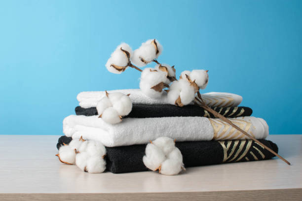 istock Stack of Black and White Towels with Cotton Branch Against Light Blue Background 2165467515