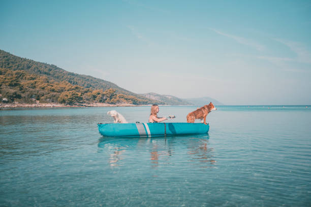 istock Young woman relaxes in inflatable raft with dog 2165468953