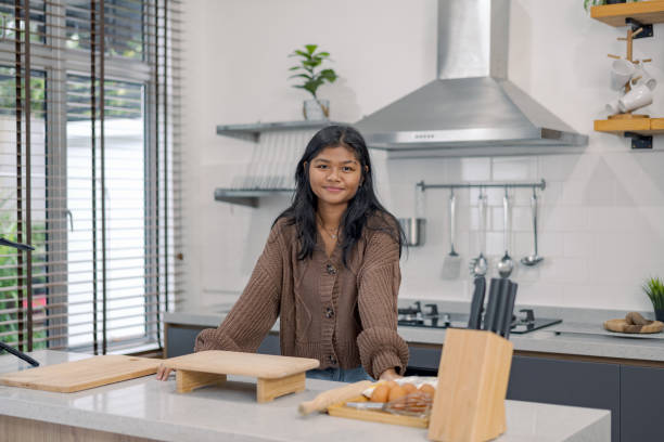 istock A young woman standing in a modern kitchen with cooking utensils and ingredients ready for baking, smiling at the camera 2165474540