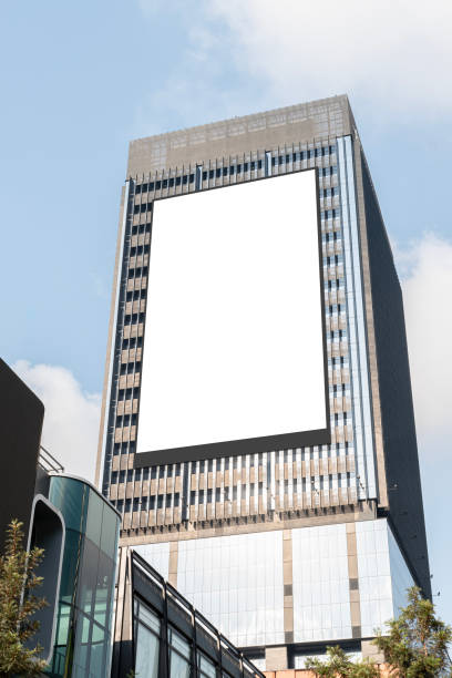 istock Mock up white vertical large LED display billboard on tower building with blue sky background .clipping path for mockup 2165480772