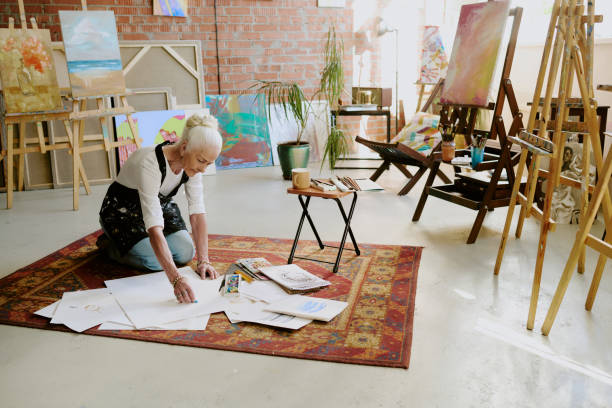 istock Creative Senior Woman Drawing While Sitting On Floor 2165481690