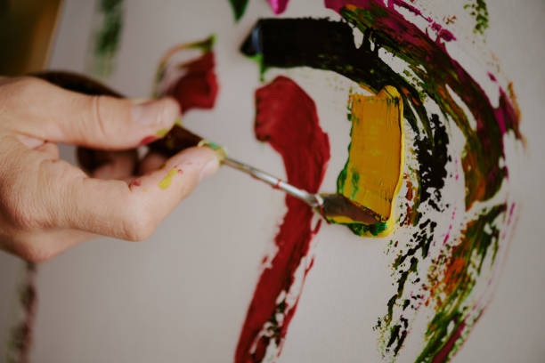 Closeup of hand of unrecognizable male artist painting with palette knife, copy space