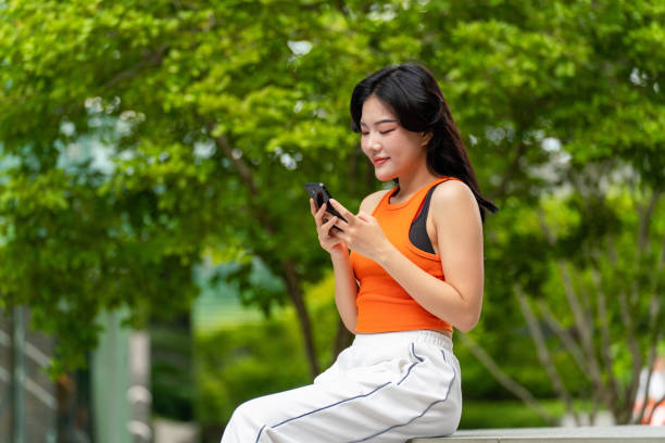 istock Young Woman Sitting In a Park Using Phone Relaxingly 2165482901