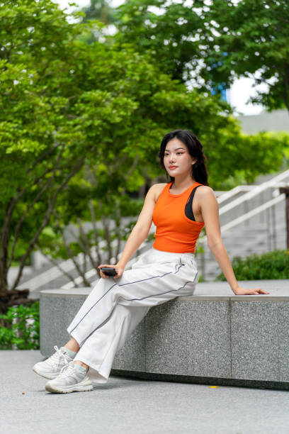 istock Young Woman Using Phone in Park Looking Away Contented 2165483044