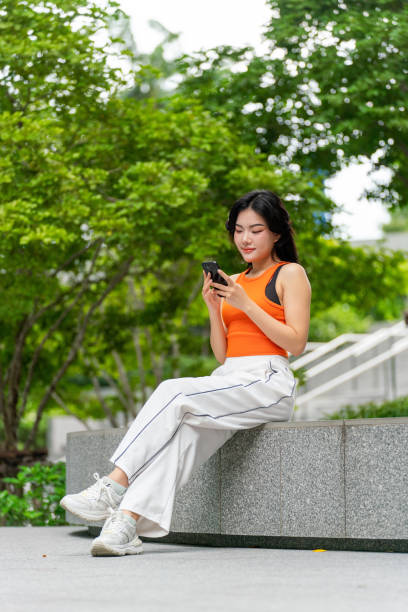 istock Young Woman Sitting In a Park Using Phone Relaxingly 2165483091
