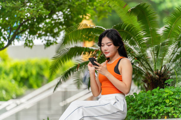 istock Young Woman Sitting In a Park Using Phone Relaxingly 2165483293