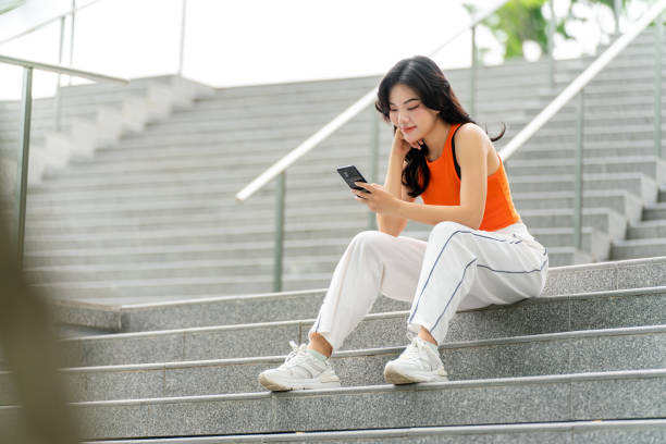 istock Young Woman Sitting In a Park Using Phone Relaxingly 2165483420