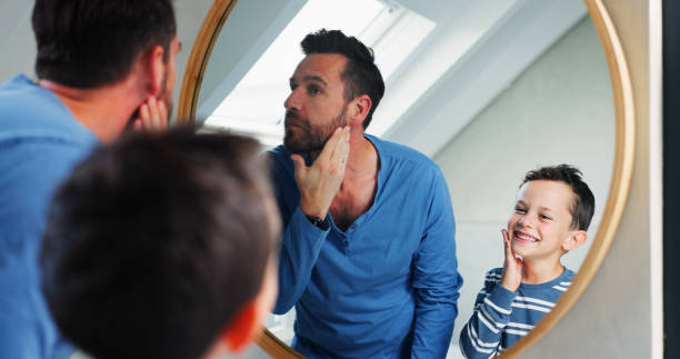 istock Morning, bathroom and dad with boy or reflection, happy and playful for growth or development in house. Father, son and mirror in home for learning facial care, grooming routine and bonding with love 2165483859