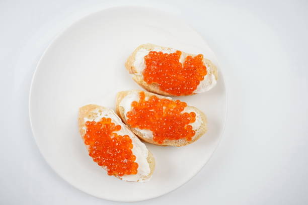 Slices of bread with red caviar on white plate