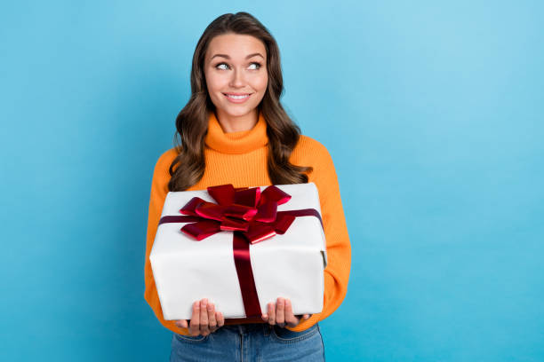 istock Photo of adorable dreamy lady wear knitted pullover holding present box looking empty space isolated blue color background 2165490018