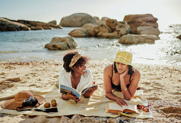 istock Two young female friends relaxing on a sandy beach in summer 2165497617