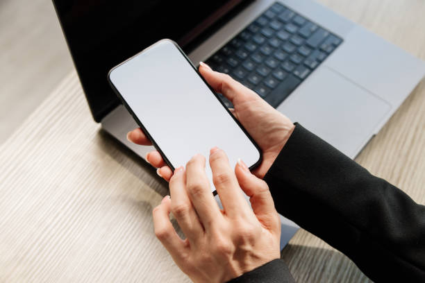 istock Close-up of female hands interacting with a blank white screen. Ideal for adding your custom design or text to promote your brand or business. 2165499428