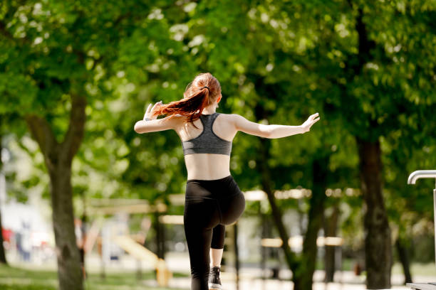 Sporty Girl Exercises In Park, View From Behind In Summer