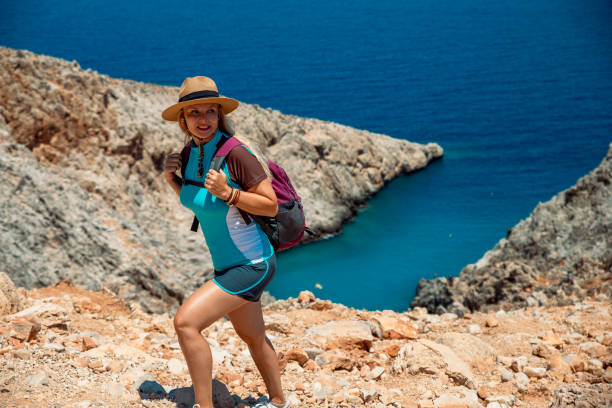 Woman backpacker hiking on dangerous path at seaside mountain in Seitan Limania (Agiou Stefanou), Akrotiri, Crete, Greece. Copy space