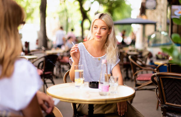 Woman with blonde hair sitting on the terrace of a café and talking to her friend stock photo