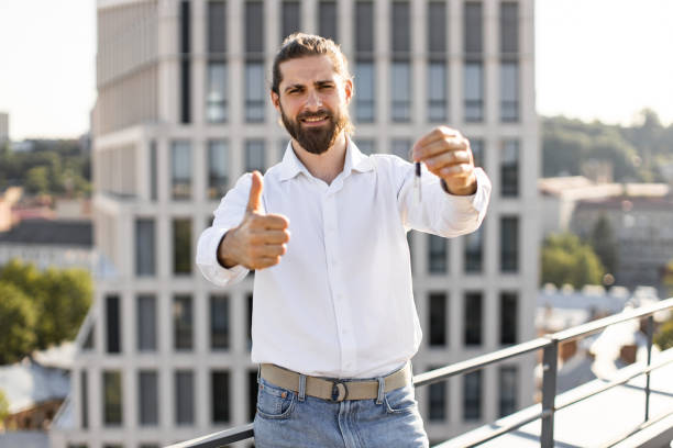 istock Happy man holding key with thumb up on rooftop 2165512620