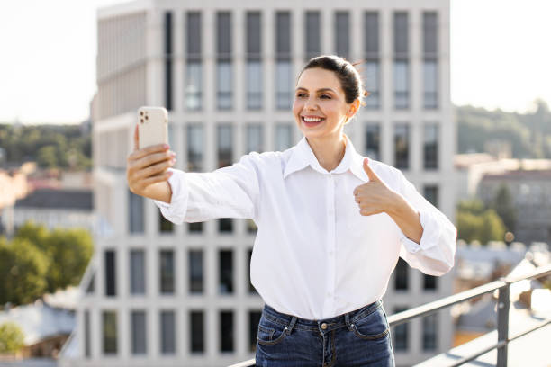 istock Smiling woman taking selfie on rooftop with thumbs up 2165512644