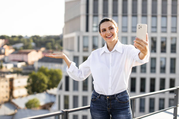 istock Smiling woman taking selfie on rooftop in urban setting 2165512647
