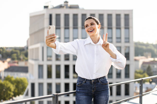 istock Woman taking selfie on rooftop making peace sign 2165512649