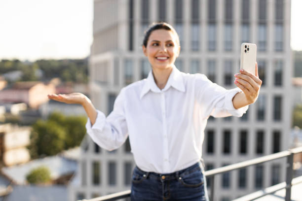 istock Smiling woman taking selfie on rooftop with smartphone 2165512652