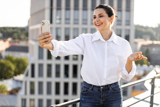 istock Smiling woman taking selfie on rooftop during sunny day 2165512668