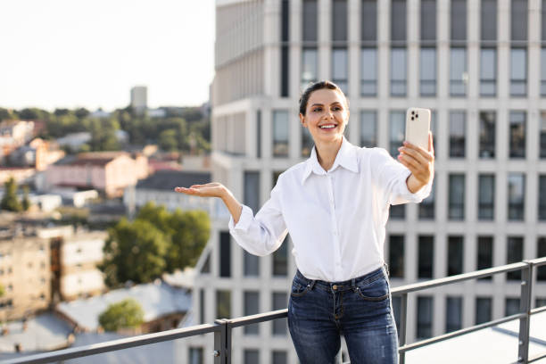 istock Woman taking selfie on rooftop with modern cityscape background 2165512670